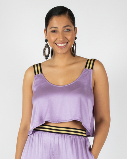 Woman wearing a lilac silk top with black and gold accents on a white background